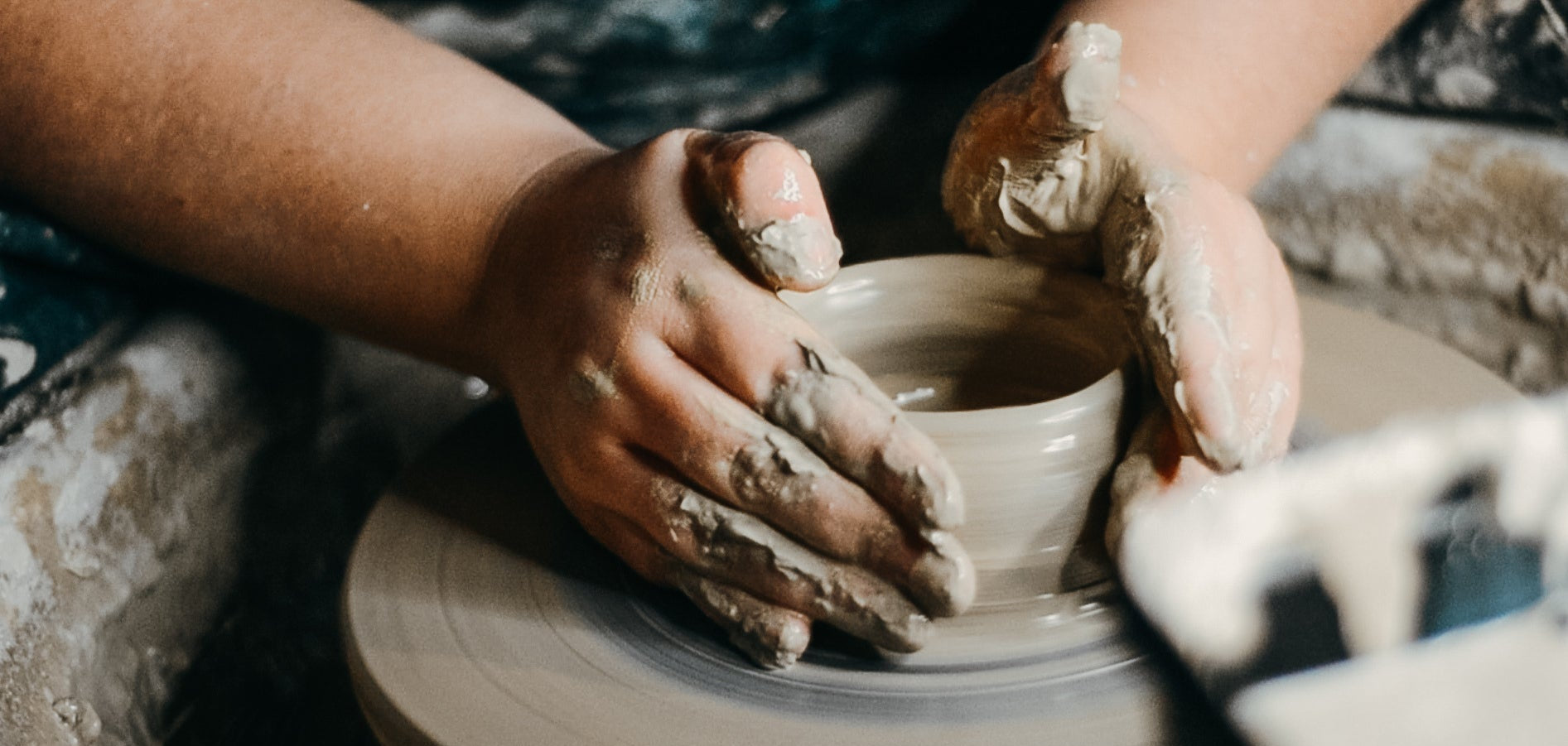 Handmade pottery in progress with hands working on a wheel